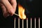 Woman igniting line of matches on black background. Space for text