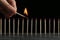 Woman igniting line of matches on table against black background