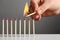 Woman igniting line of matches on table against grey background