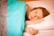 Woman iling on pillow in bed, covered with blanket