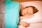 Woman iling on pillow in bed, covered with blanket