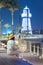 Woman and the illuminated decorative lighthouse near the parking lot of yachts and ships in the Dubai Creek Marina Harbor