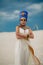 Woman in image of egyptian queen Nefertiti stands in desert with whip in her hand