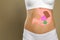 Woman with image of stomach full of junk food drawn on her belly against beige background. Unhealthy eating habits