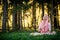 Woman in Indian clothes sitting in sunny green forest meditating