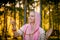 Woman in Indian clothes in sunny forest meditating and smiling with rosary in hands