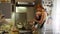 Woman with an infant boy sitting in a sling cooks soup for a dinner and cleans up at the kitchen and then kisses the kid