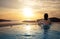 Woman in infinity swimming pool at golden sunset. Summer vacation holiday