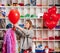 a woman inflates of helium from a red balloon.