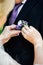 Woman inserting the boutonniere in buttonhole man in suit