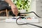 Woman inserting power plug into extension cord on floor indoors, closeup.