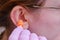 A woman inserts earplugs into her ear in protective medical gloves, close-up