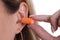Woman inserts orange earplugs into ears closeup