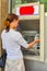 A woman inserts a plastic card into an ATM for withdrawing cash