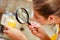 Woman inspecting food with magnifying glass.