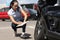 Woman inspector writing in documents on clipboard near broken car. Auto insurance