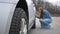 Woman inspects a flat or damaged tire on the rear of her SUV on the road