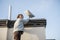 Woman installing Starlink satellite dish on roof of her house