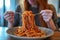 woman intently eating spaghetti, plate piling high