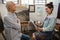 Woman interacting with senior man while sketching on canvas