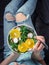 Woman in jeans at bed, holding vegan salad bowl