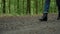 Woman in jeans and boots walks in forest, closeup side ground view