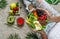 Woman in jeans holding fresh healthy green salad with quinoa, peach, greens, avocado, berries, melon in bowl on light background