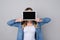 Woman in jeans shirt, isolated on grey background hiding her face behind digital tablet with blank touchscreen studying education