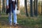 Woman in jeans walks holding basket of mushrooms among trees closeup crop body