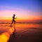 Woman jogger on the beach at sunset.