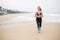 Woman is jogging along the seashore on an overcast day