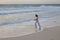 Woman jogging on the edge of the sandy beach at sunrise