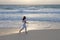 Woman jogging on the edge of the sandy beach at sunrise