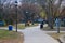 A woman jogging in an orange jacket on a smooth footpath in the park with other people on the footpath