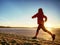 Woman jogging on winter beach run. Female athlete runner