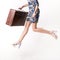 Woman in a jump in a hurry with a suitcase