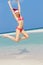 Woman Jumping On Beach Wearing Santa Hat