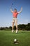 Woman jumping over good golf shot.