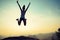 Woman jumping on sunrise rocky mountain peak