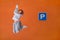 A woman jumps up near a Parking sign. Man and levitation. White jacket.