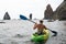 Woman kayak sea. Happy woman kayaks in sea, capturing outdoor memory with happy tourist taking photo. Volcanic mountains