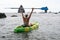 Woman kayak sea. Happy woman kayaks in sea, capturing outdoor memory with happy tourist taking photo. Volcanic mountains