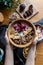 Woman keeping the breakfast bowl with granola, milk, bananas, nuts, and berries