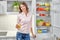 Woman keeping glass of orange juice and posing at kitchen