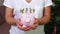 Woman keeping pink piggy bank with British pound sign concept