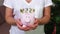 Woman keeping pink piggy bank with euros sign concept