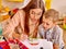 Woman with kids holding colored paper and glue in