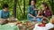 Woman and kids on a picnic at the forest edge - eating