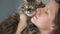 Woman kisses and rubs her face against a very fluffy tabby cat to express her love and affection, slow motion