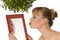Woman kissing herself in a mirror under mistletoe